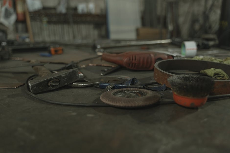 A selection of various tools scattered on a workbench in an industrial setting.