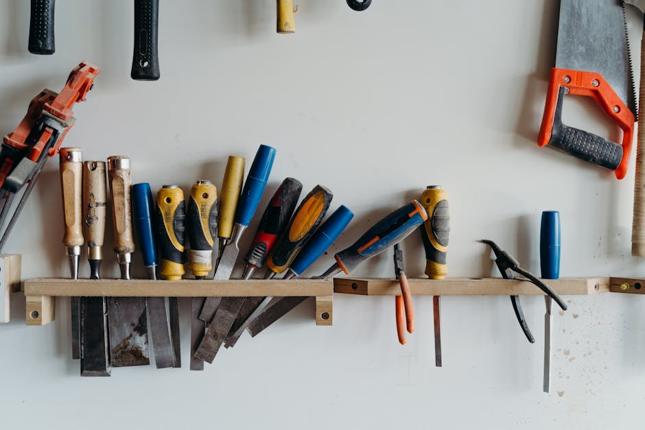 A neatly arranged collection of hand tools including chisels, saws, and screwdrivers in a workshop.
