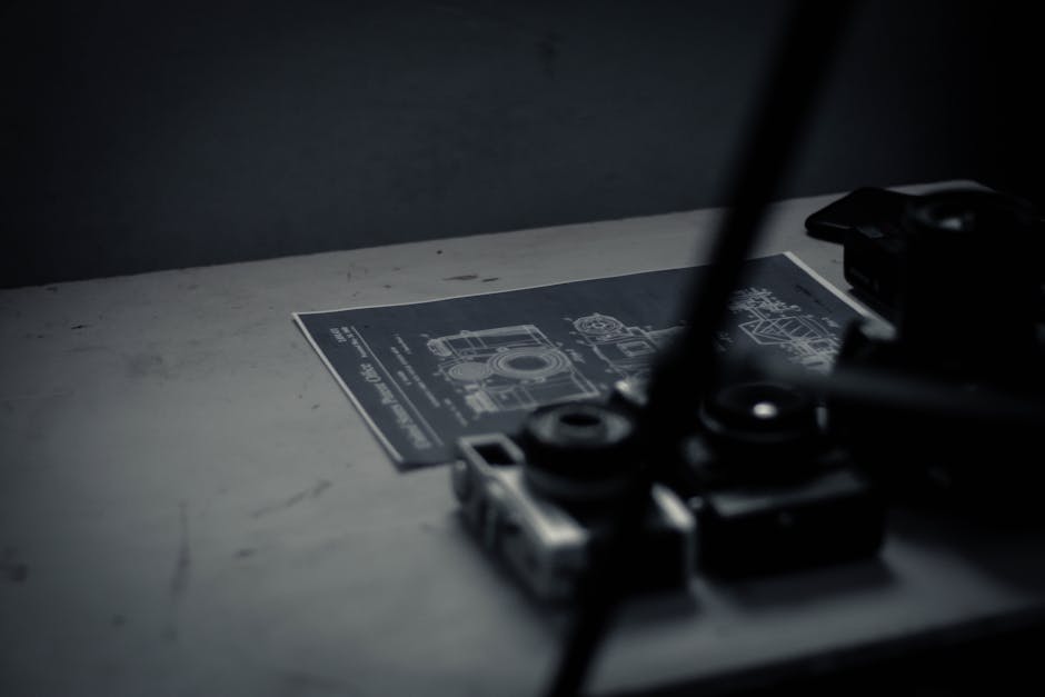 From above old fashioned film cameras placed on desk near paper sheet with using instructions in workshop